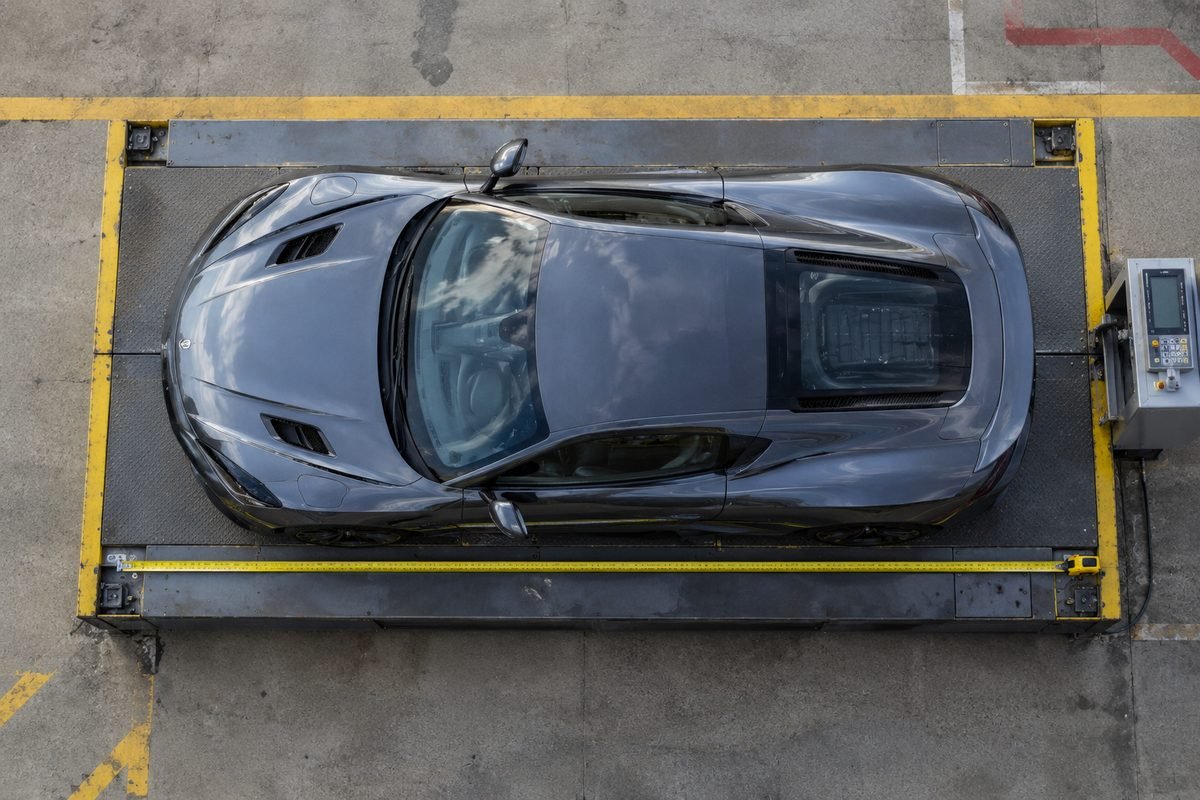 Top-down view of a luxury car on a cargo scale with a measuring tape showing its length